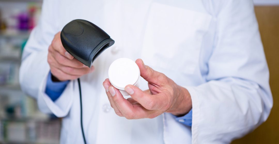 Pharmacist using barcode scanner on medicine container in pharmacy